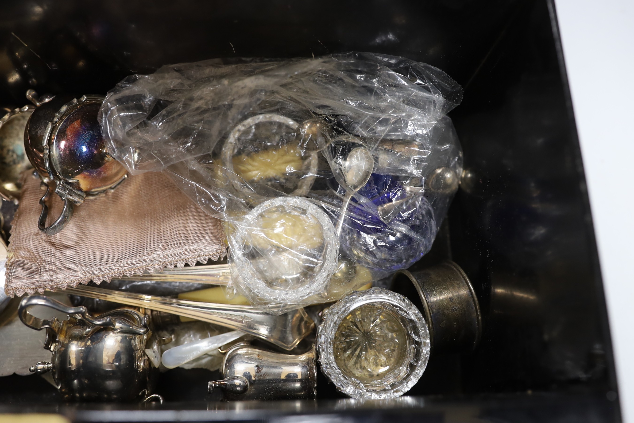 A tin box containing silver plated cutlery and cruets etc